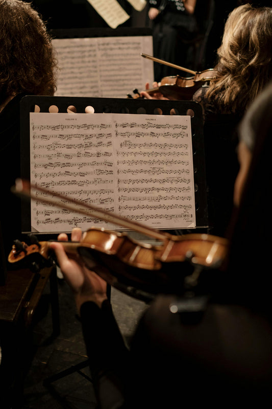 A dramatic view of a symphony orchestra performing on stage with warm lighting, representing the immersive experience of feeling music through technology.