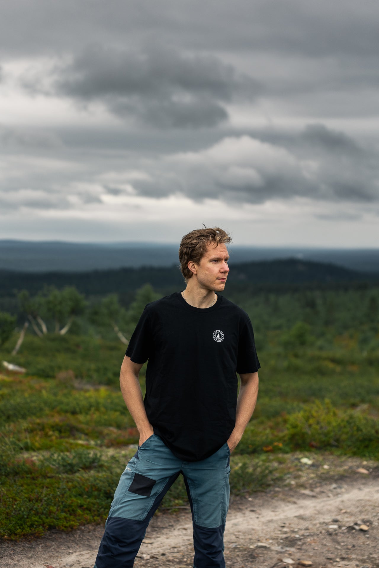 Jetro Luhtaa wearing the sustainable black organic cotton t-shirt by Novapuro featuring a minimalist chest logo in a Nordic landscape.