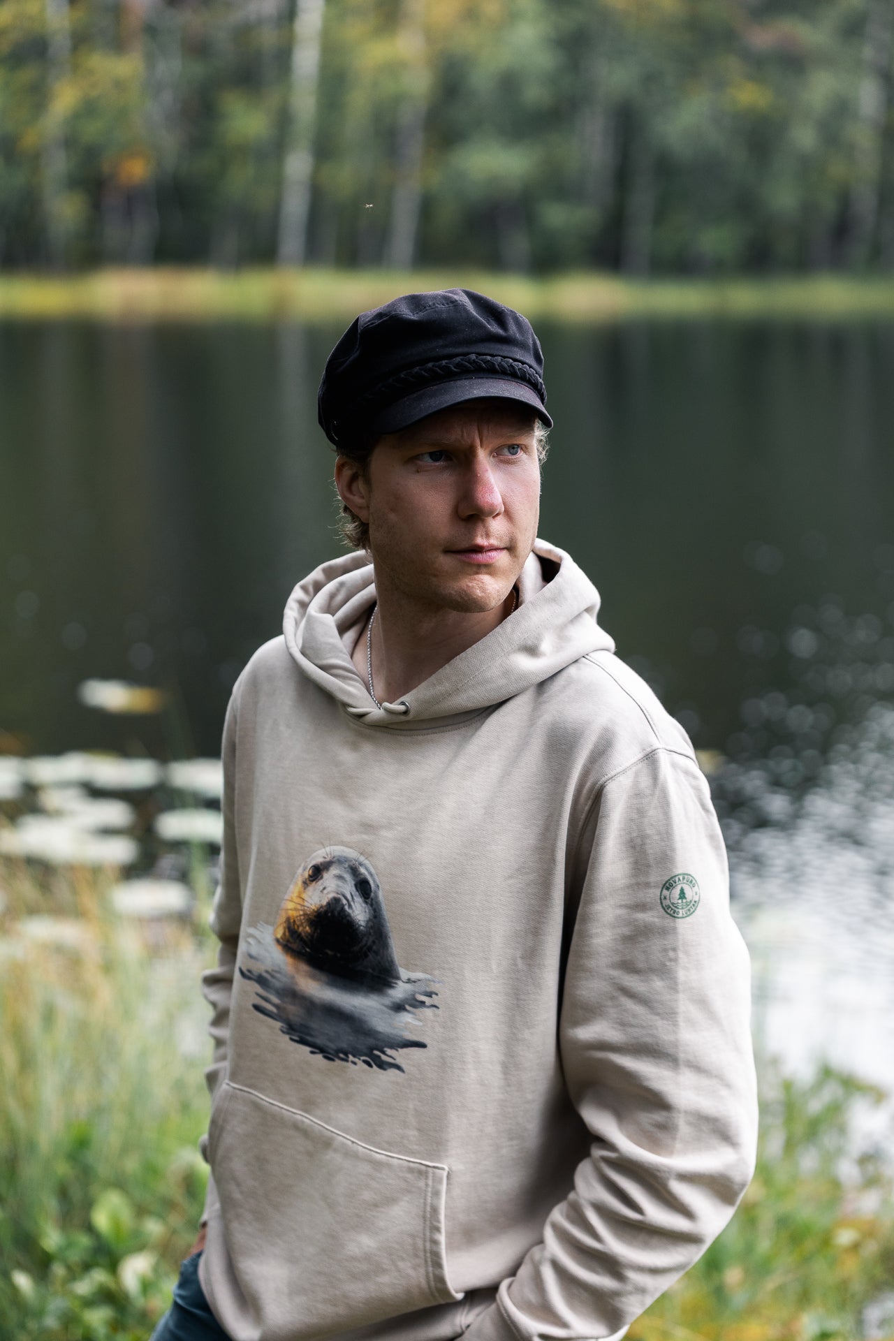 Eco-friendly Novapuro x Jetro Luhtaa beige hoodie showcasing a nature-inspired seal print and the collaboration sleeve logo.