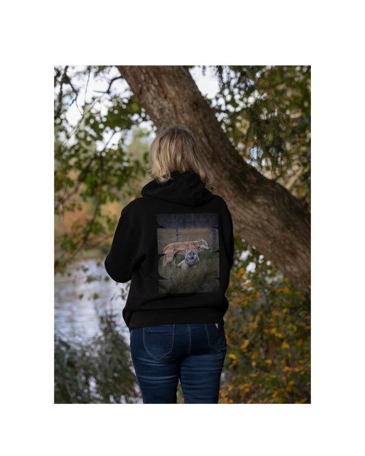 Female model in a forest wearing a black unisex organic cotton hoodie with the 'Leaders of the Pack' wolf duo back print. Sustainable Nordic nature apparel.