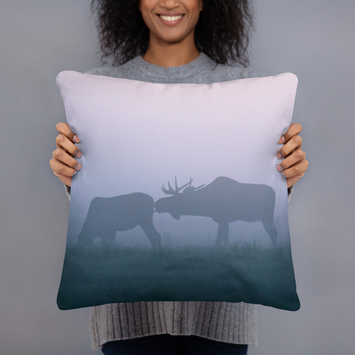 A person holding the soft 'Misty Moose' throw pillow, showcasing the captivating wildlife art and premium fabric