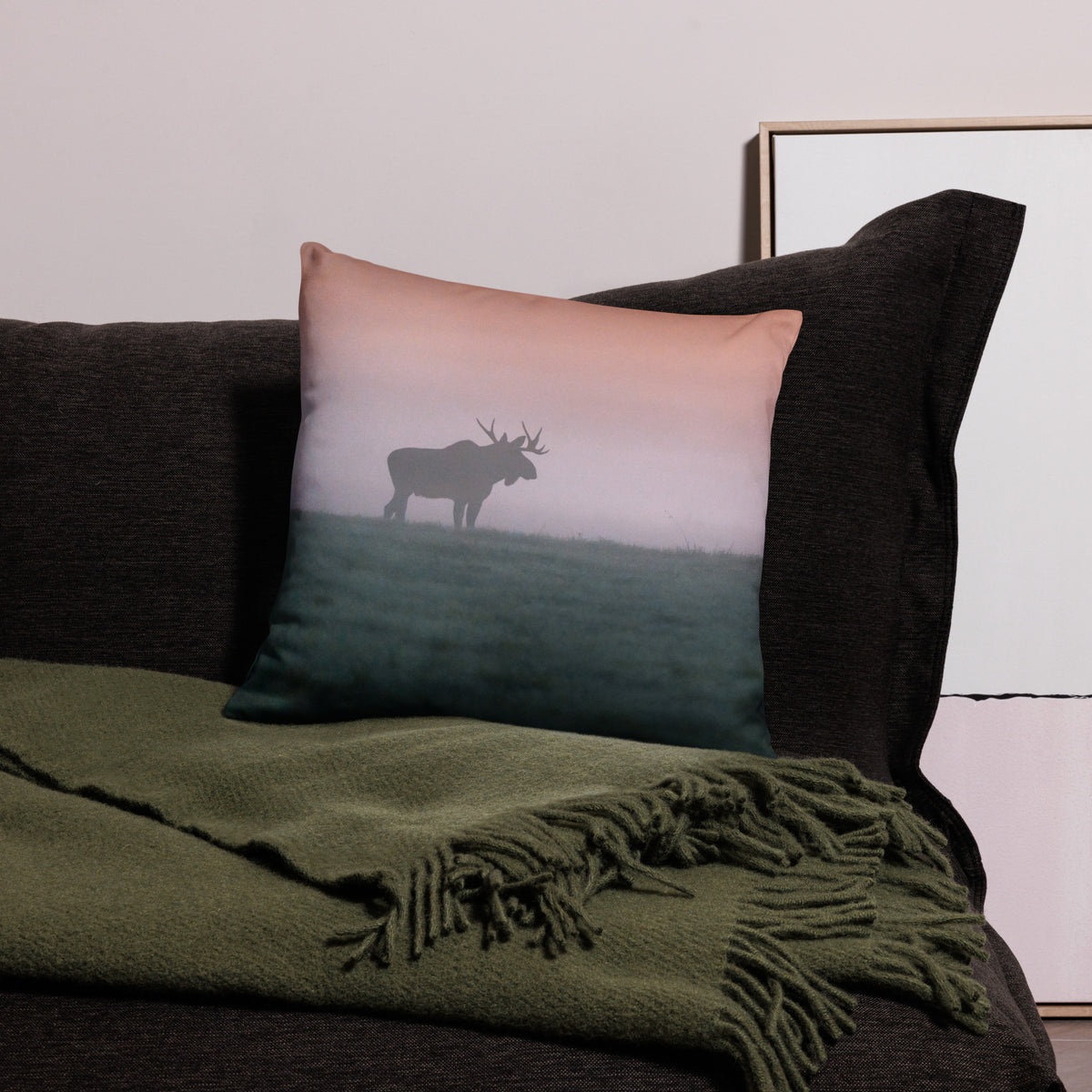 A stylish premium throw pillow featuring a distressed splash-edge print of a majestic bull moose by Mikko Monto, placed in a cozy home setting.