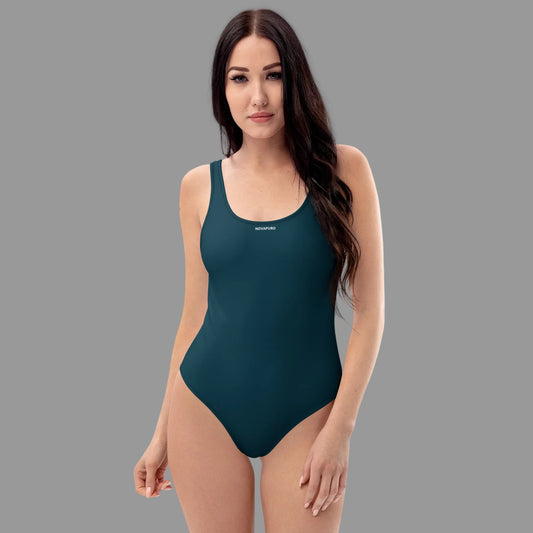 Model wearing deep ocean blue Novapuro Signature one-piece swimsuit with subtle chest logo