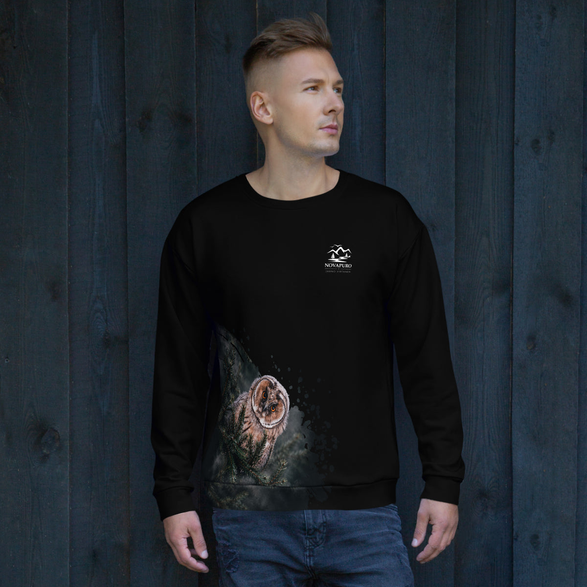 A person wearing the Novapuro x Jarno Virtanen black recycled sweatshirt featuring a Nordic long-eared owl chick print on the lower side.