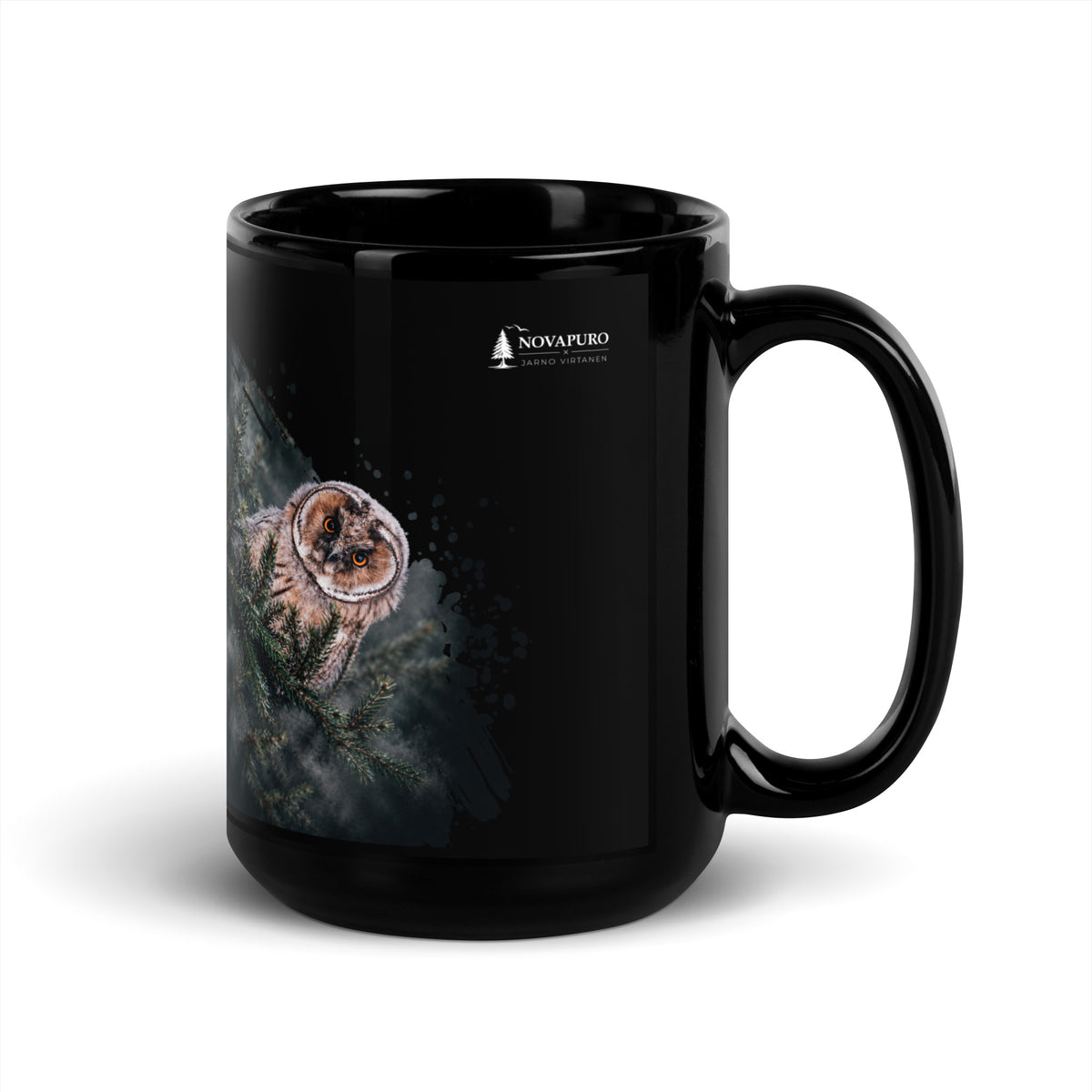 A black glossy ceramic mug featuring a Nordic long-eared owl chick print by Jarno Virtanen, sitting on a desk next to a notebook.