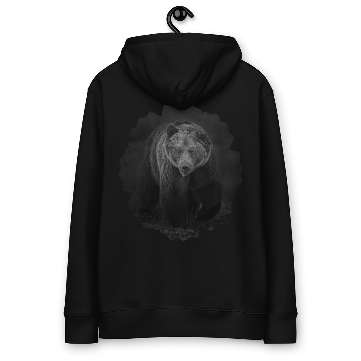 Auli Leivonen wearing a black Novapuro organic cotton hoodie with a majestic Nordic bear photography print on the back, standing outdoors by a lake.