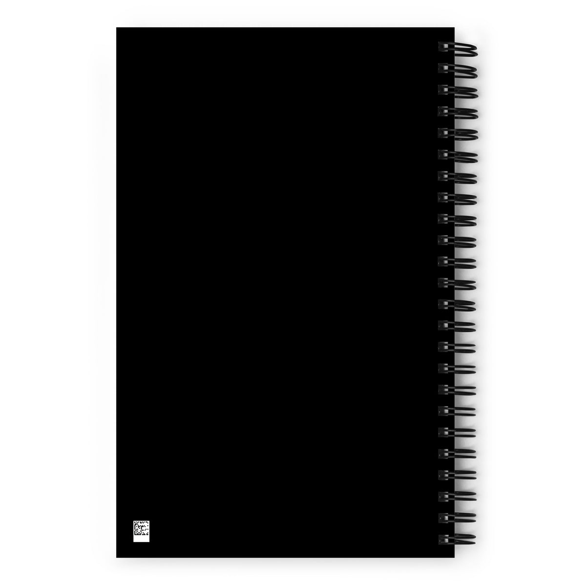A black wire-bound spiral notebook featuring a Nordic long-eared owl chick print by Jarno Virtanen, placed on a white desk next to a coffee cup.