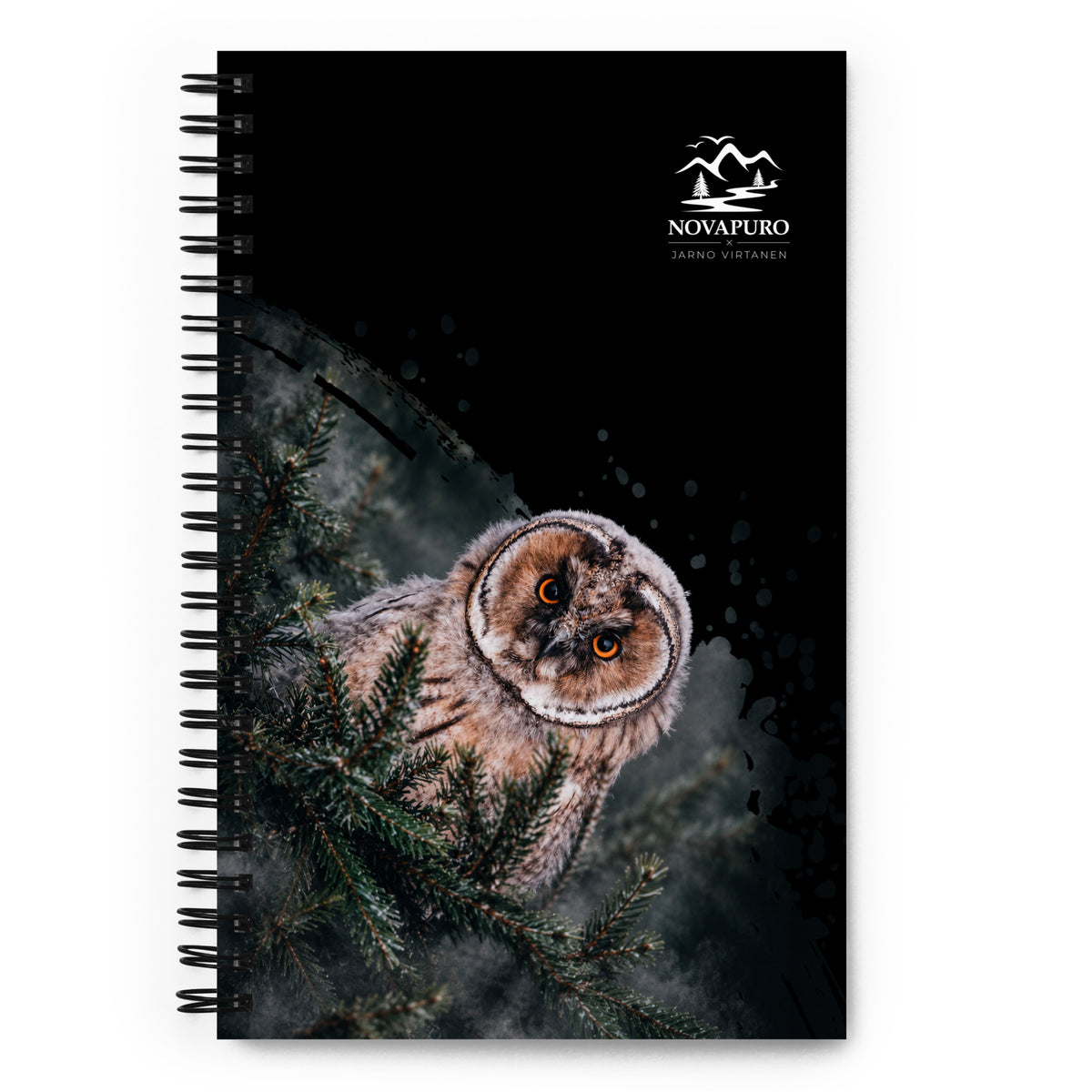 A black wire-bound spiral notebook featuring a Nordic long-eared owl chick print by Jarno Virtanen, placed on a white desk next to a coffee cup.