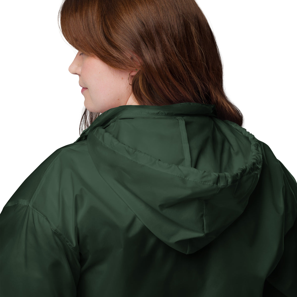 A smiling woman wearing the dark green Novapuro x Annette Thomé-Marttinen 'Nordic Fox' windbreaker jacket, featuring a minimalist white fox illustration on the chest.