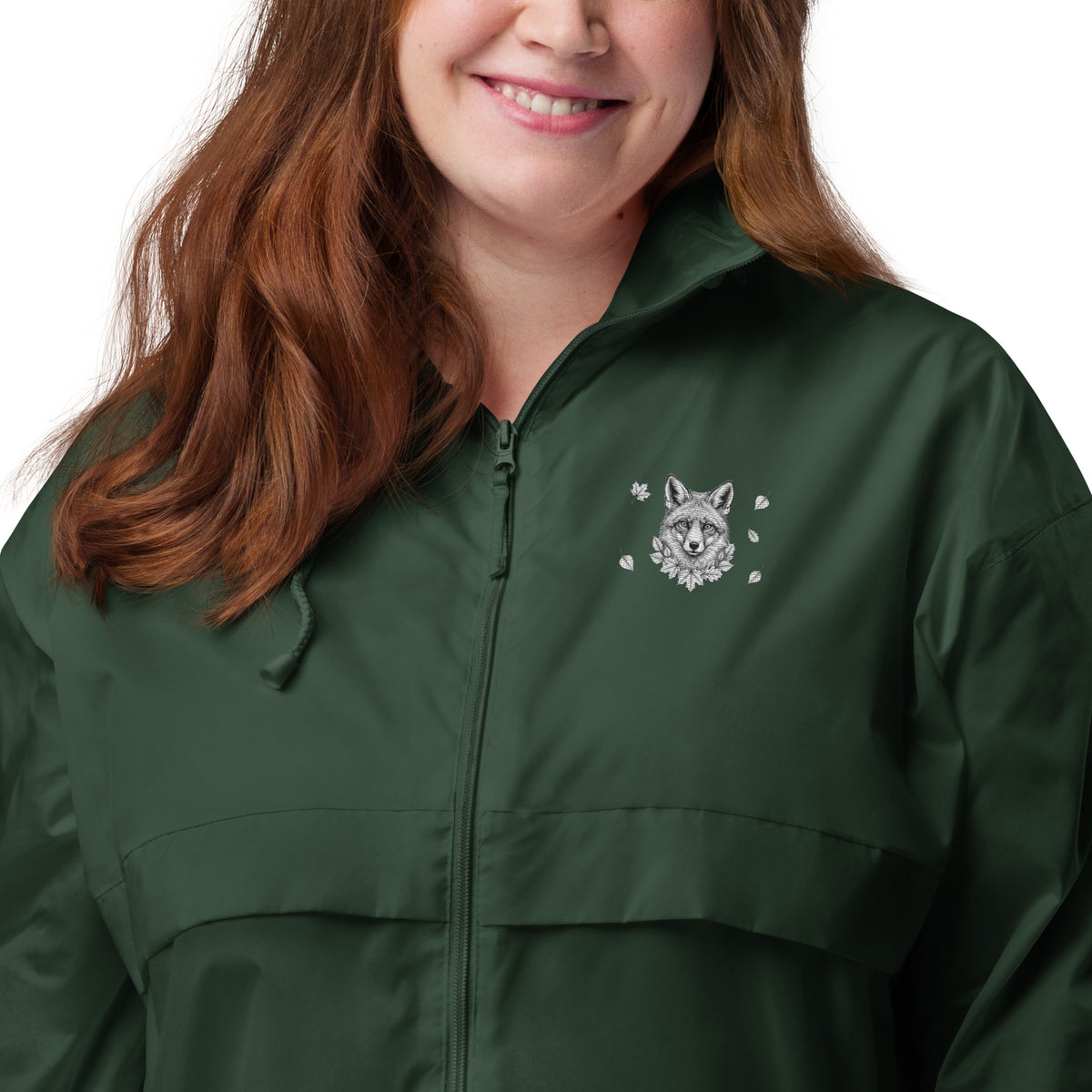 A smiling woman wearing the dark green Novapuro x Annette Thomé-Marttinen 'Nordic Fox' windbreaker jacket, featuring a minimalist white fox illustration on the chest.