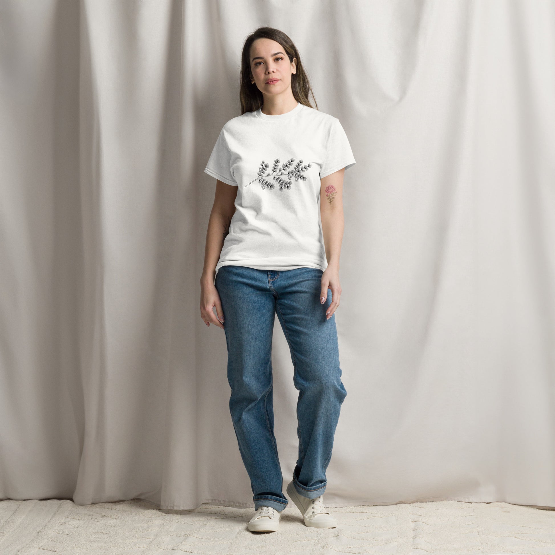 Front view of a white classic t-shirt featuring an elegant minimalist black ink illustration of a Nordic spruce branch centered on the chest.