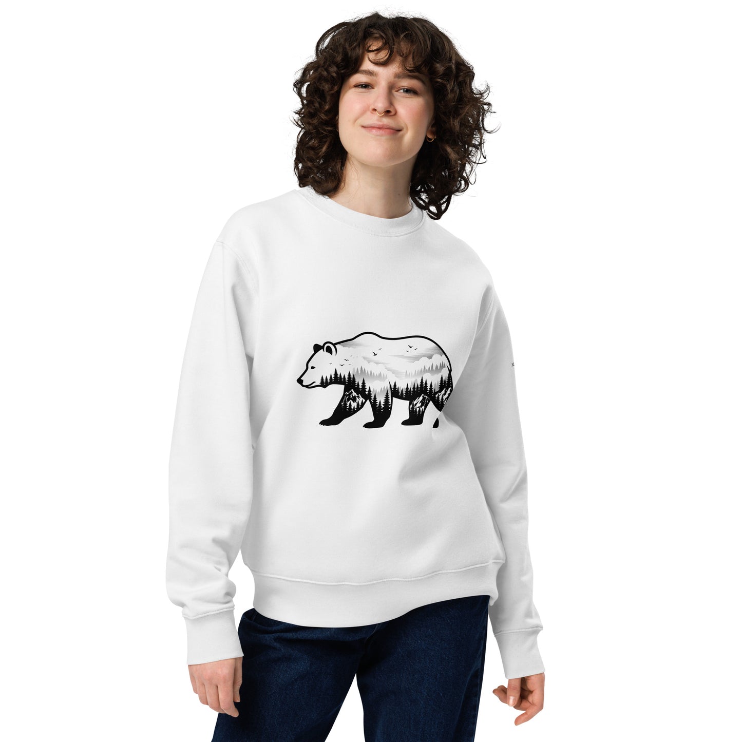 A model wearing a white unisex organic cotton sweatshirt featuring a minimalist double exposure graphic of a bear and pine forest.