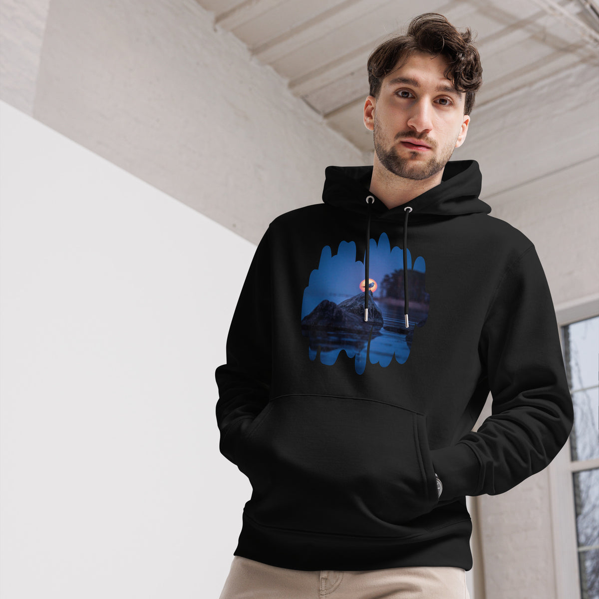 Front view of a male model wearing the black unisex organic eco hoodie featuring the 'Nordic Sunrise' wildlife photography by Niko Laurila x Novapuro.