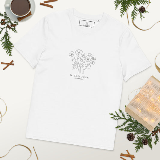 A woman wearing a crisp white premium organic cotton t-shirt featuring an elegant, minimalist single line art illustration of Nordic wildflowers.