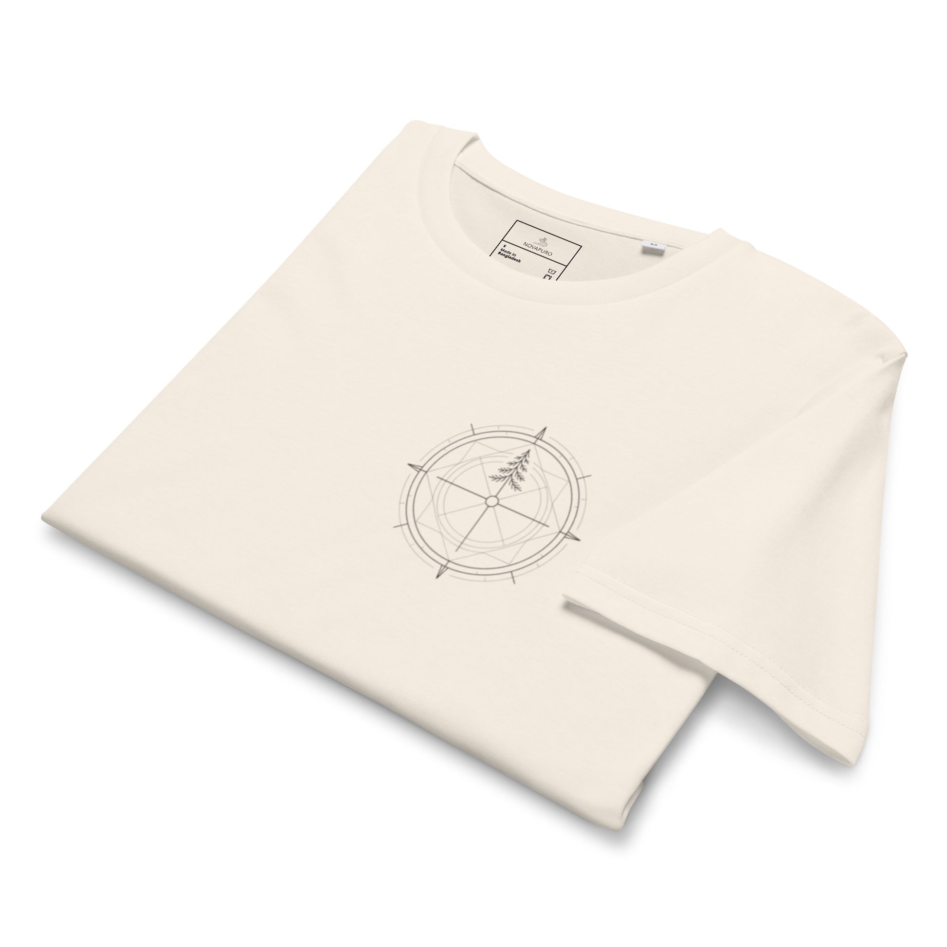 Folded cream white organic cotton t-shirt highlighting a minimalist compass and pine tree print on the chest.