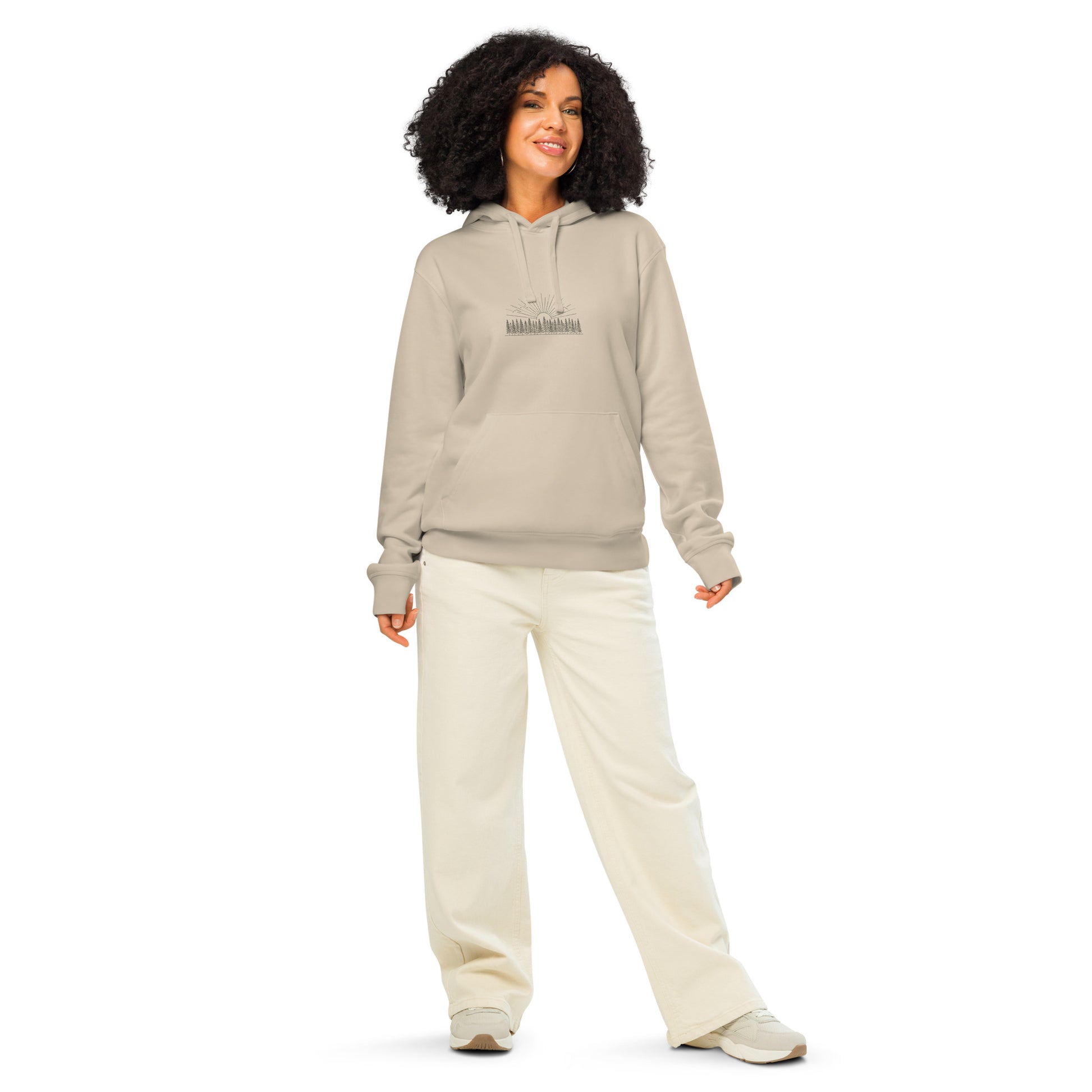 Model wearing a natural beige organic cotton hoodie featuring a minimalist Nordic forest and sunrise graphic by Novapuro