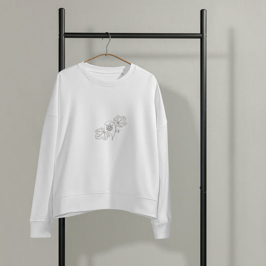 White Novapuro women's organic cotton crewneck sweatshirt hanging on a black garment rack, featuring a minimalist botanical cloudberry line art illustration on the left chest